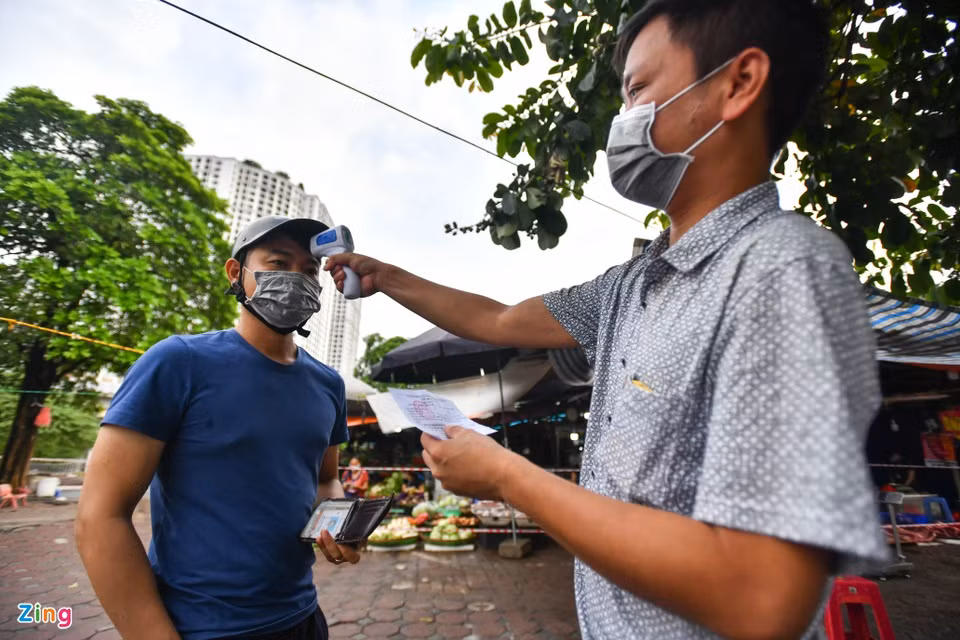 Người dân ra vào chợ được đo thân nhiệt và kiểm tra phiếu đi chợ.
