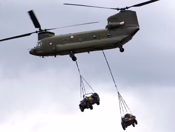 Một chiếc trực thăng CH-47 Chinook mang theo 2 xe quân sự.