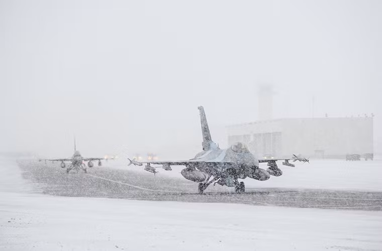 Một phi đội tiêm kích đa năng F-16 Fighting Falcons của Không quân Mỹ cất cánh từ một căn cứ không quân ở Alaska trong khi tuyết rơi khá dày.