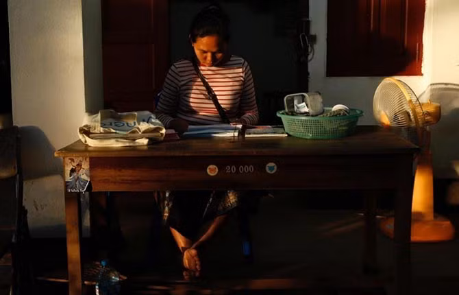 Một phụ nữ đang bán vé cho du khách muốn leo núi Phousi.