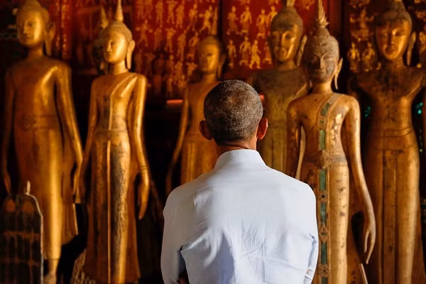 Ông chăm chú ngắm nhìn các bức tượng ở chùa Wat Xieng Thong. Tên gọi của chùa trong tiếng Lào có nghĩa là "kinh thành vàng".