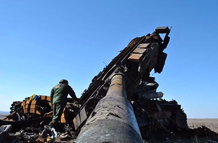 Tay súng phe ly khai miền đông Ukraine đang xem xét tháp pháo chiếc tăng T-64 của Quân đội Ukraine bị bật khỏi thân xe.