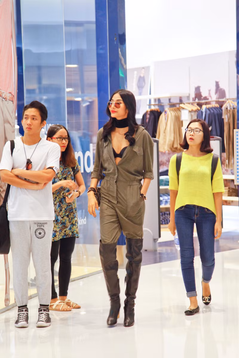 Cùng với jumpsuit màu xanh quân đội đang hot trở lại, Hoàng Thùy còn táo bạo để lộ áo bra đen gợi cảm, kết hợp cùng đôi bốt đen cao đến đầu gối và cặp kính mặt gương cá tính.