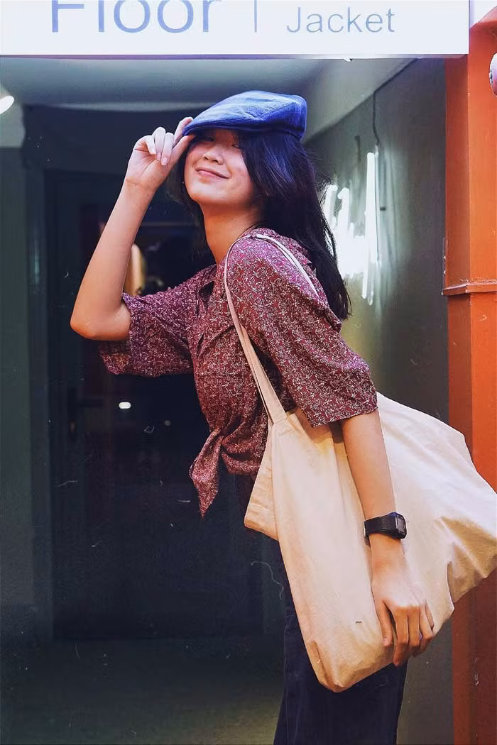Mũ bê rê, áo sơ mi hoa nhí buộc vạt, quần tối màu cùng phụ kiện là chiếc túi vải giản dị, nhìn Á hậu Bảo Ngọc rất phong cách và cá tính.