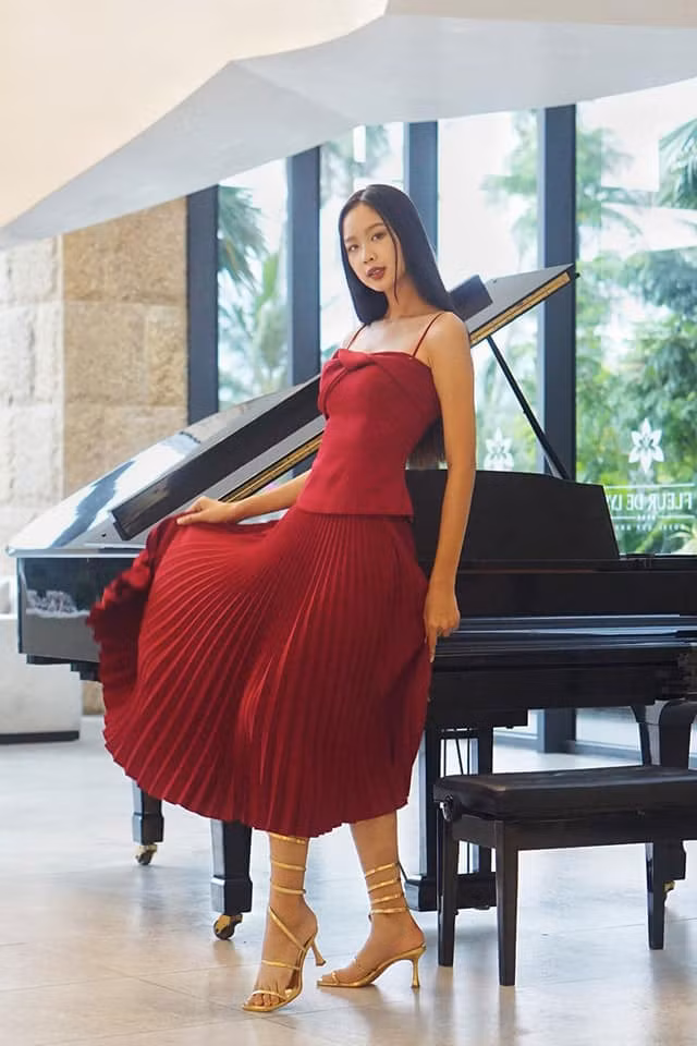 Bộ váy xếp li kết hợp với áo hai dây màu đỏ đô khiến người đẹp Cần Thơ thêm phần thanh lịch.