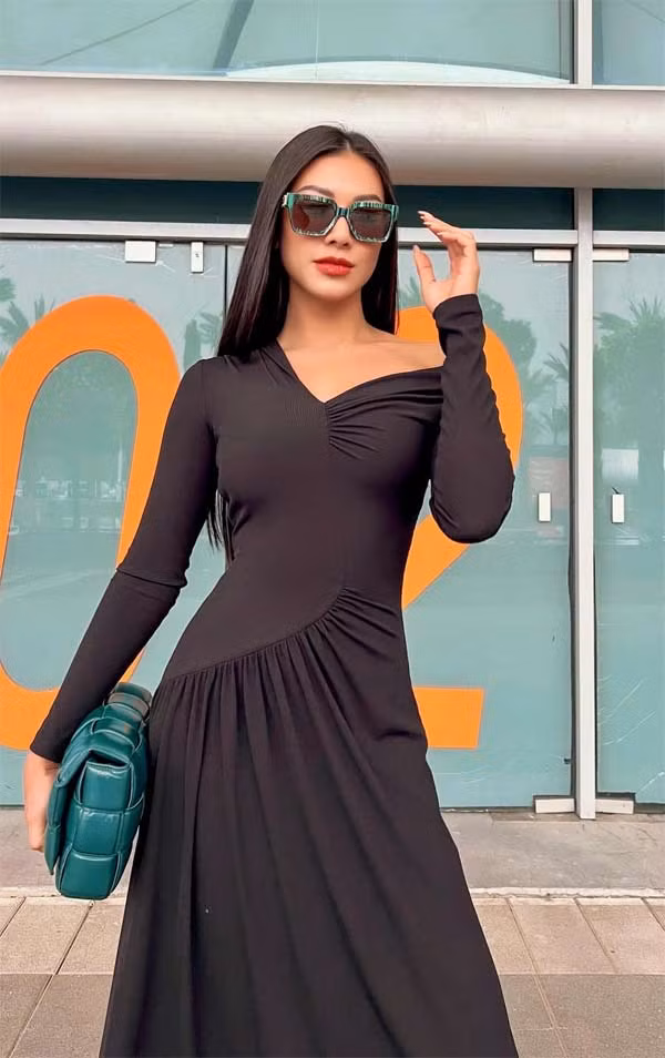 Kim Duyên khoe dáng với chiếc váy đen dài ôm sát phần trên, phụ kiện là chiếc kính và túi màu xanh cổ vịt. Set đồ tối giản nhưng vẫn mang lại hiệu ứng thị giác tuyệt vời.