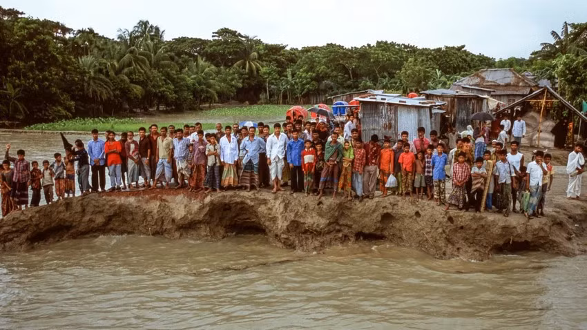 Một số người dân đứng trên phần còn lại của một con đường ở đảo Bhola, Bangladesh vào năm 2005. Khu vực này vốn nằm ở cửa sông đồng bằng sông Hằng đang ở trong tình trạng bị xói mòn nghiêm trọng do mực nước biển dâng. Ảnh: Gary Braasch.