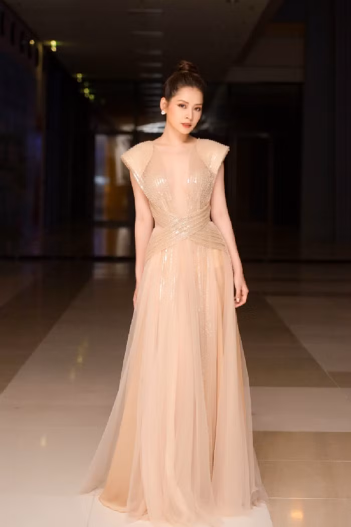 Đây không phải lần đầu Chi Pu sải bước với thiết kế váy dài bồng bềnh. Không ít lần cô trở thành tâm điểm, thu hút sự quan tâm của truyền thông khi lên đồ với mẫu đầm thanh lịch, gợi cảm. Trong hình, người đẹp diện mẫu đầm khoét ngực sâu hun hút gam màu nude gợi cảm. Mẫu đầm tôn lên đường cong cơ thể và vóc dáng thanh mảnh của nữ ca sĩ.