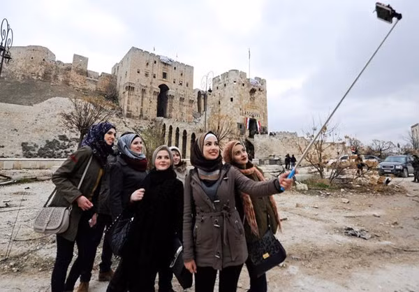 Một nhóm phụ nữ cười tươi chụp hình lưu niệm trước khu Thành cổ Aleppo.