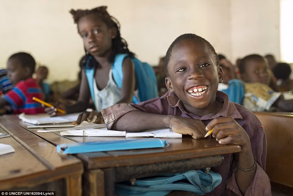 Bé Usher Sanca, 7 tuổi, cười tươi ngồi trong lớp học tại ngôi trường Ponta Nova do quỹ UNICEF hỗ trợ ở làng Ponta Nova, Guinea Bissau.