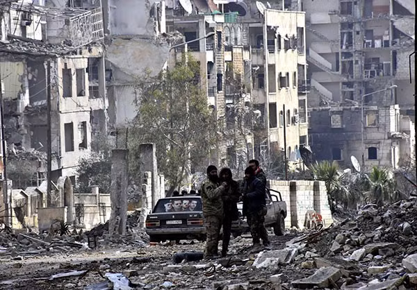 Binh sĩ quân đội Syria đứng giữa đống đổ nát ở thành phố Aleppo mới giải phóng.