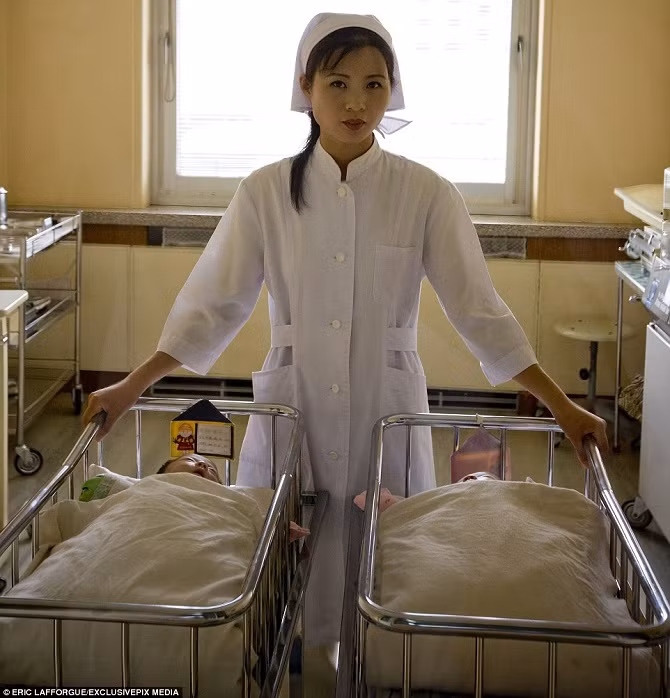 Nữ y tá đứng cạnh hai bé sơ sinh trong bệnh viện ở Triều Tiên.