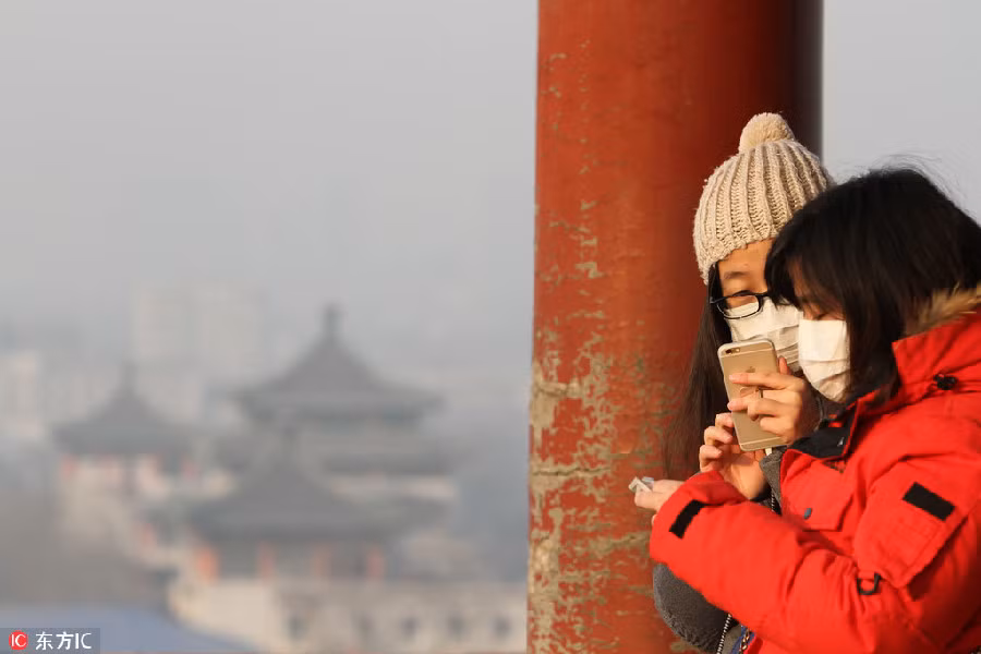 Hai du khách đeo khẩu trang chụp ảnh tại Công viên Jingshan ở Bắc Kinh trong ngày báo động đỏ ô nhiễm.