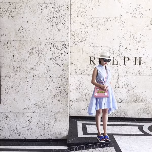 Yến Trang kết hợp váy đầm xanh phấn cùng sandals quai chéo, không quên phụ kiện kính mắt và mũ vành tròn yêu thích đi kèm.