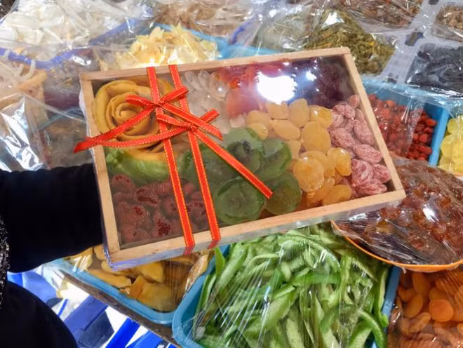 Sau đóng gói, mứt vẫn không tem nhãn. Khay gỗ 1,6kg giá 430.000 đồng, là sản phẩm hiếm ở khu phố này do giá thành cao mà khối lượng ít, chỉ có sẵn tại một quầy ở đầu phố. Đây cũng là quầy duy nhất phủ nilon bảo quản thực phẩm
