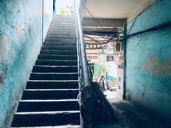 Đi qua quán cà phê cóc đầu hẻm là cầu thang lên xuống làm bằng sắt, nhỏ hẹp, tối tăm. Ảnh: T.A.