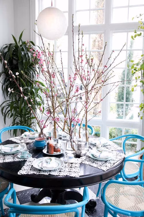 Để trang trí bàn ăn với phong cách lãng mạn, bạn có thể sử dụng nhiều lọ thủy tinh nhỏ và cắm các cành đào cao. Ảnh: Kenhphunu.
