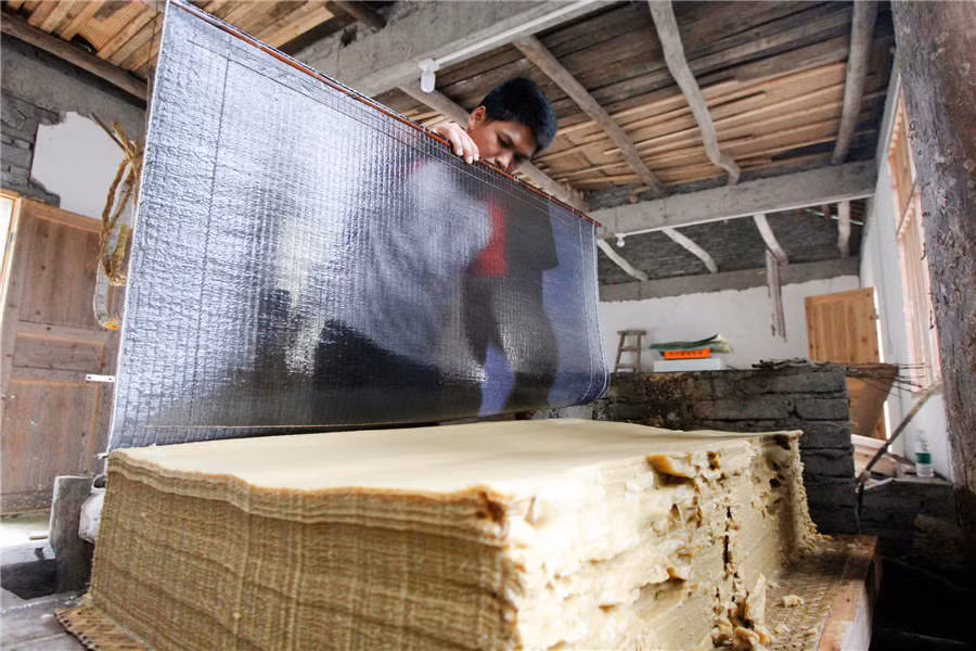 Khi nước khô, bột giấy se lại và trang giấy dần hiện ra.