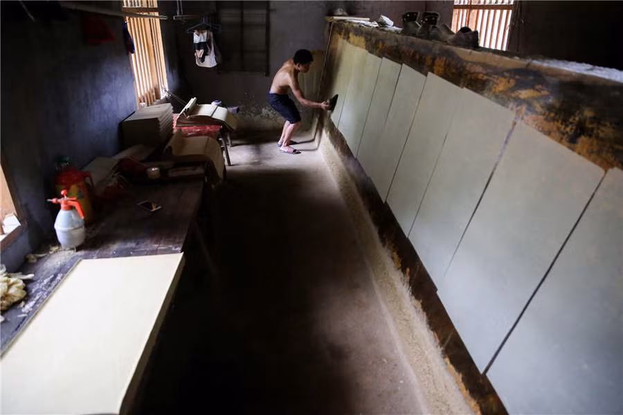 Cuối cùng, những tờ giấy lên tường và cán cho thật phẳng. Nguồn ảnh: Xinhua.