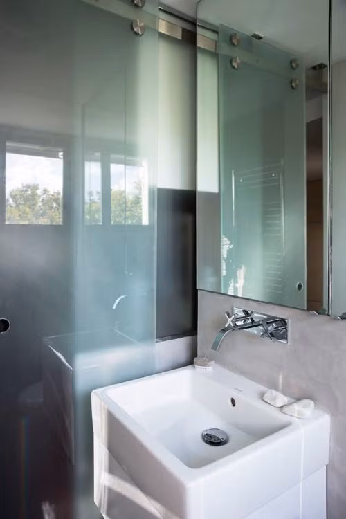 Toàn bộ bức tường phía trên bồn rửa mặt và bồn cầu lắp gương soi khổ lớn giúp lằm tăng cảm giác rộng lớn cho căn phòng.