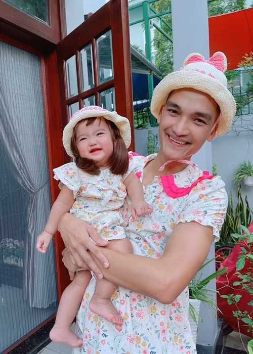 Mạc Văn Khoa dành nhiều thời gian chăm sóc con gái. Để con cười, anh đóng giả vợ, mặc váy, đội nón y chang vợ. Ảnh: FBNV