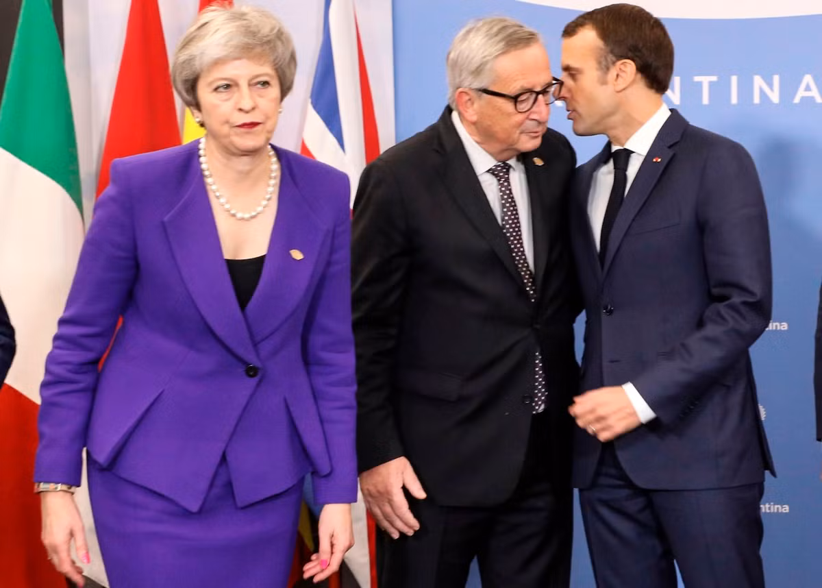 Thủ tướng Anh Theresa May đi phía trước khi Tổng thống Pháp Emmanuel Macron và Chủ tịch Ủy ban Châu Âu Jean-Claude Juncker đang “thì thầm” phía sau. Được biết, EU và Anh đã đạt được một thỏa thuận về Brexit (Anh rời EU), nhưng Tổng thống Macron đe dọa sẽ “đánh chìm” thỏa thuận này bằng cách yêu cầu quyền đánh bắt cá trong vùng biển của Anh.