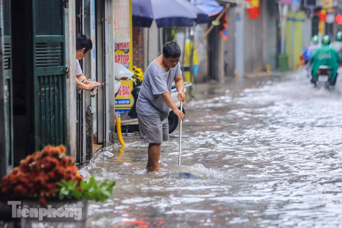 Người đàn ông đang cố quét nước ra ngoài không cho tràn vào nhà. 