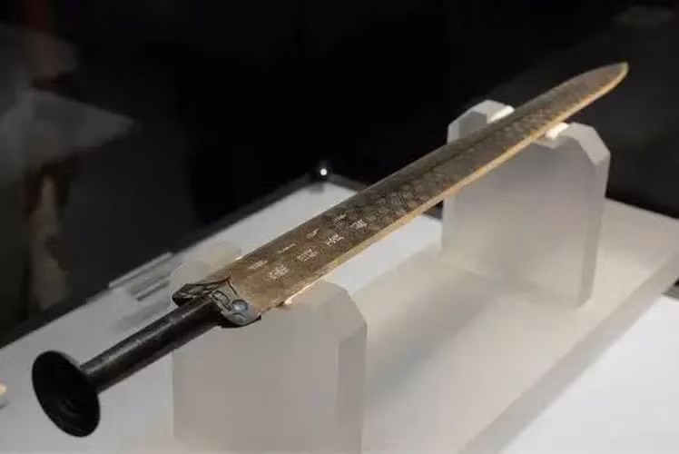 Năm 1965, trong một ngôi mộ cổ ở Kinh Châu, tỉnh Hồ Bắc, Trung Quốc, các nhà khảo cổ học phát hiện một thanh kiếm bằng đồng nguyên vỏ, dài 56 cm, rộng 4,6 cm, có 11 vòng tròn đồng tâm ở đáy chuôi kiếm.