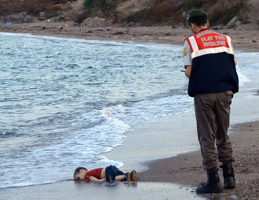 Hình ảnh lịch sử "Cậu bé Syria trên bờ biển" chụp năm 2015 gây chấn động thế giới khi chụp Aylan Kurdi, 3 tuổi, đến từ thị trấn Kobahi phía bắc Syria chết trên bờ biển gần khu nghỉ dưỡng Bodrum, Thổ Nhĩ Kỳ. Tấm hình này là bằng chứng cho những hành trình tị nạn khắc nghiệt và đầy thương vong.