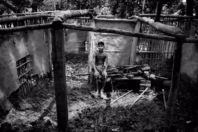 Cậu Suraj Jamal Mallick, 12 tuổi, ngồi ở căn nhà cũ nay không còn sử dụng. Khi mực nước dâng thêm mỗi năm, nhiều người sống tại các vùng ven biển buộc phải rời nơi ở.