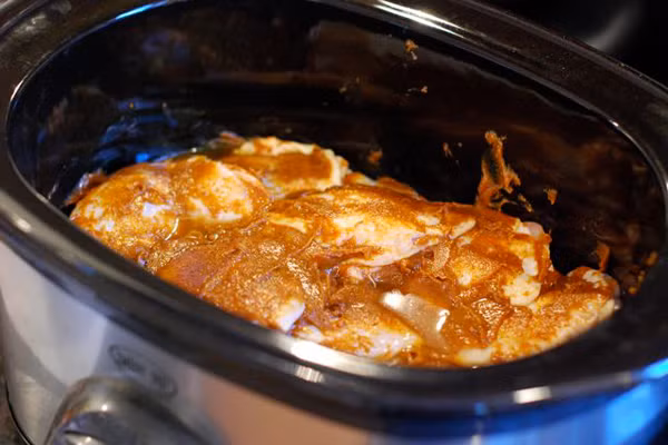Cho nước dùng gà, sốt hoisin, sốt cà chua, mật ong, tỏi, tương ớt Sriracha, gừng và dầu mè vào nồi rồi trộn lên. Sau đó, tiếp tục cho thịt gà vào đảo đều cho ngấm nước sốt. Đậy vung lại, đun trên lửa to từ 3-4 tiếng. 