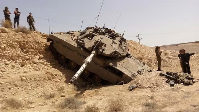 Cỗ xe tăng được xếp vào loại hiện đại nhất như Merkava IV của quân đội Israel vẫn chịu cảnh "sa lầy" và đang chờ cứu hộ. Nhiều bình luận của cộng đồng mạng cho rằng chiếc Merkava này chỉ việc cài số lùi là ra được hố đất hoặc thậm chí kíp lái có thể dùng xẻng xúc đất tạo lối ra cho xe tăng thay vì chờ cứu hộ. Nguồn ảnh: Ynetnews.