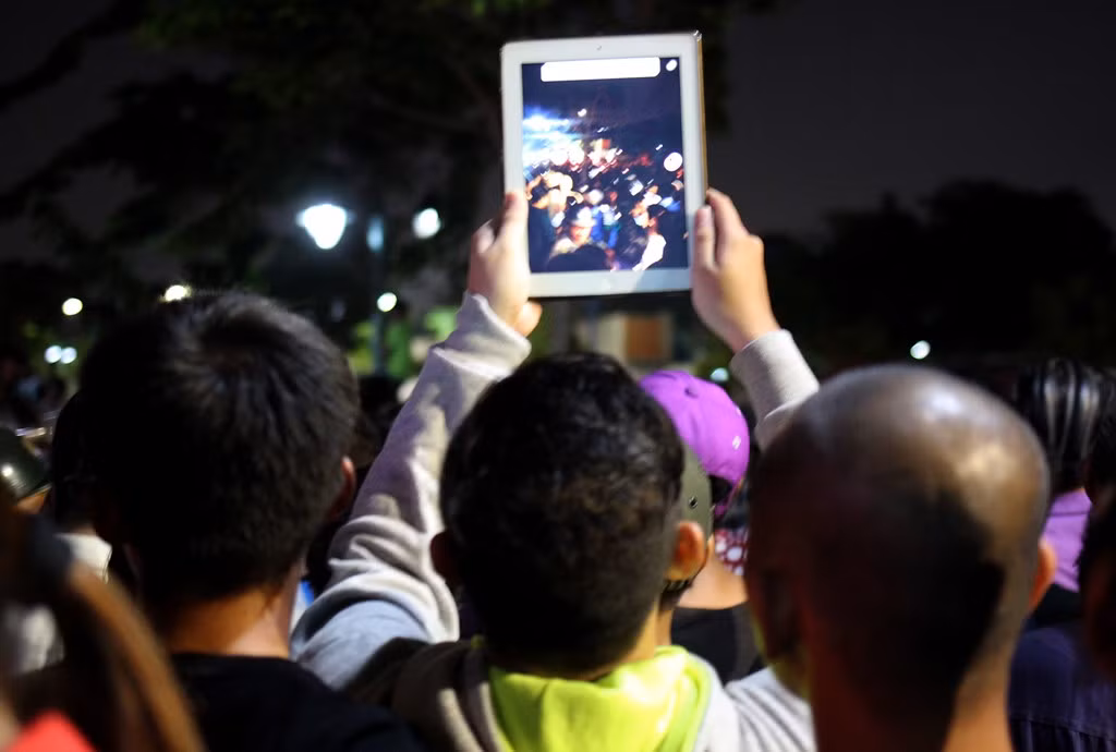 Một thanh niên thậm chí còn chen lấn với đám đông để được vị trí thuận lợi dùng iPad livestream Facebook.