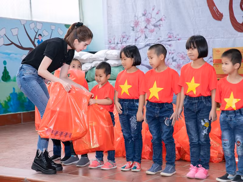 Hình ảnh Ngọc Trinh ăn mặc giản dị, phát quà cho trẻ em trong chuyến từ thiện.
