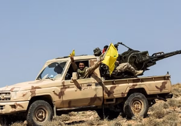 Chiến binh Hezbollah vẫy cờ và giơ tay biểu tượng chiến thắng khi ngồi trên xe quân sự. Ảnh: FNA.