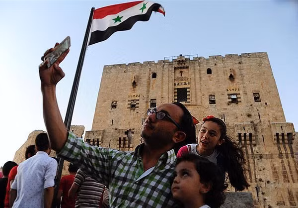 Người dân chụp ảnh lưu niệm tại một địa điểm ở thành phố Aleppo. Ảnh: FNA.