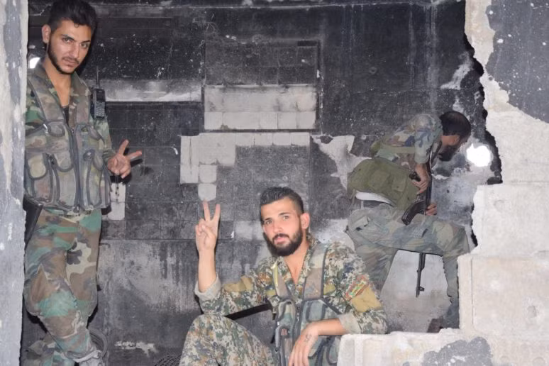 Binh sĩ Syria giơ tay biểu tượng chiến thắng trong ngôi nhà đổ nát ở phía Đông thủ đô Damascus. Ảnh: AMN.