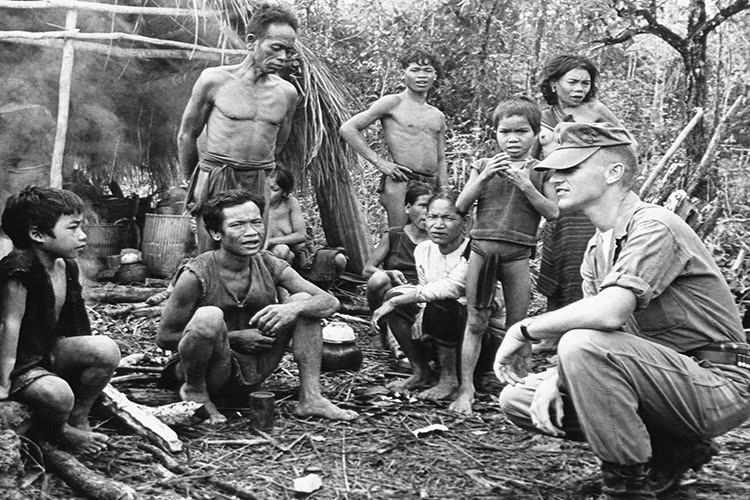 Như một điều tất yếu, ngày 8/3/1965, các đơn vị thủy lục chiến Mỹ đầu tiên đổ bộ lên bờ biển Đà Nẵng, đưa cuộc chiến sang một trang mới. Trong ảnh là một sĩ quan Mỹ nói chuyện với một nhóm người dân tộc trong một ấp tập trung ở miền trung Việt Nam trong năm 1962, lúc này người Mỹ vẫn chỉ tham gia ở mức cố vấn quân sự. The Atlantic.