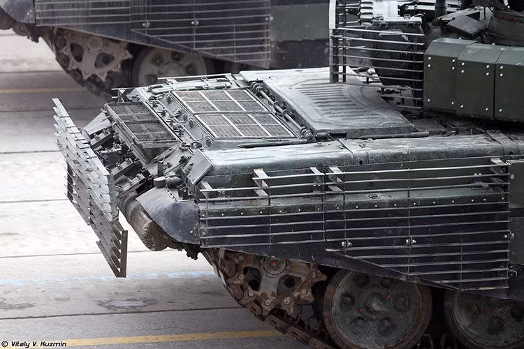 Trong khi đó tấm giáp váy bằng cao su cứng ở hai bên thân trên T-72B3 trước đây cũng được thay thế bằng lớp giáp bảo vệ đa lớp nhằm tăng khả năng bảo vệ hai bên thân xe, còn phần đuôi xe nơi chứa động cơ cũng được bọc thêm lớp giáp lồng. Với hệ thống giáp mới trên có thể nói hệ thống phòng vệ thụ động trên T-72B3M đã tới giới hạn cuối cùng của mình. Nguồn ảnh: Vitaly Kuzmin.