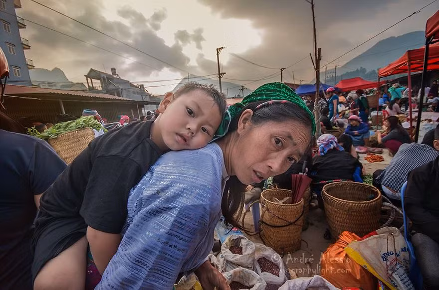 Bé trai theo mẹ tới một phiên chợ tấp nập người bán, người mua với các mặt hàng phong phú, đa dạng.