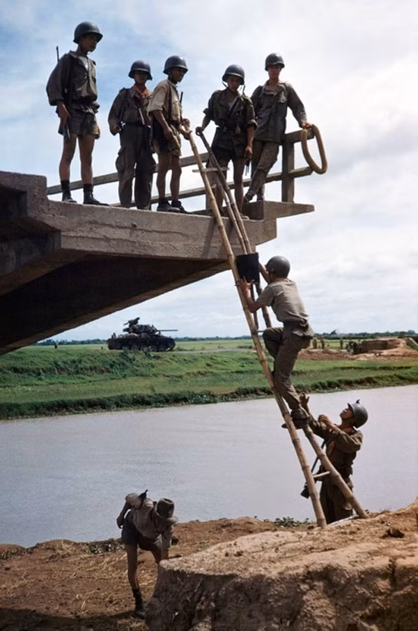Binh sĩ người Việt trong quân đội Pháp vượt sông bằng một cây cầu đang xây dựng dở dang, phía Tây Nam Định.