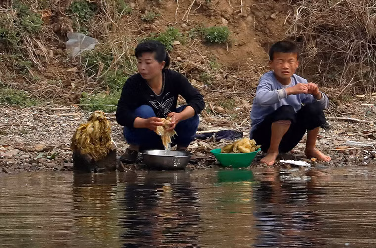 Người phụ nữ Triều Tiên và một em nhỏ rửa rau bên bờ sông Áp Lục.
