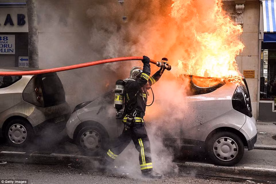 Lính cứu hỏa dập lửa cho chiếc ô tô đang bốc cháy trên đường phố thủ đô Paris ngày 1/5.