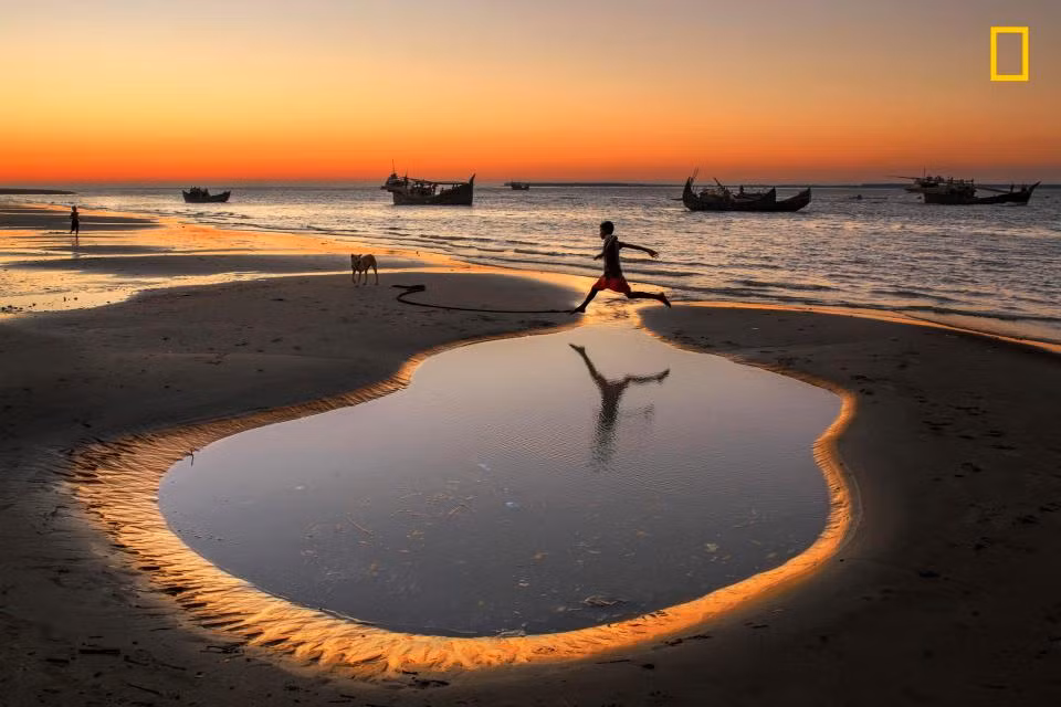 Một bé trai nhảy qua vũng nước trên biển ở làng Cox’s Bazar Dry, Bangladesh. Theo nhiếp ảnh gia Yousuf Tushar, hơn 5.000 gia đình kiếm sống bằng cách đánh bắt thủy sản và chế biến cá khô ở ngôi làng này.