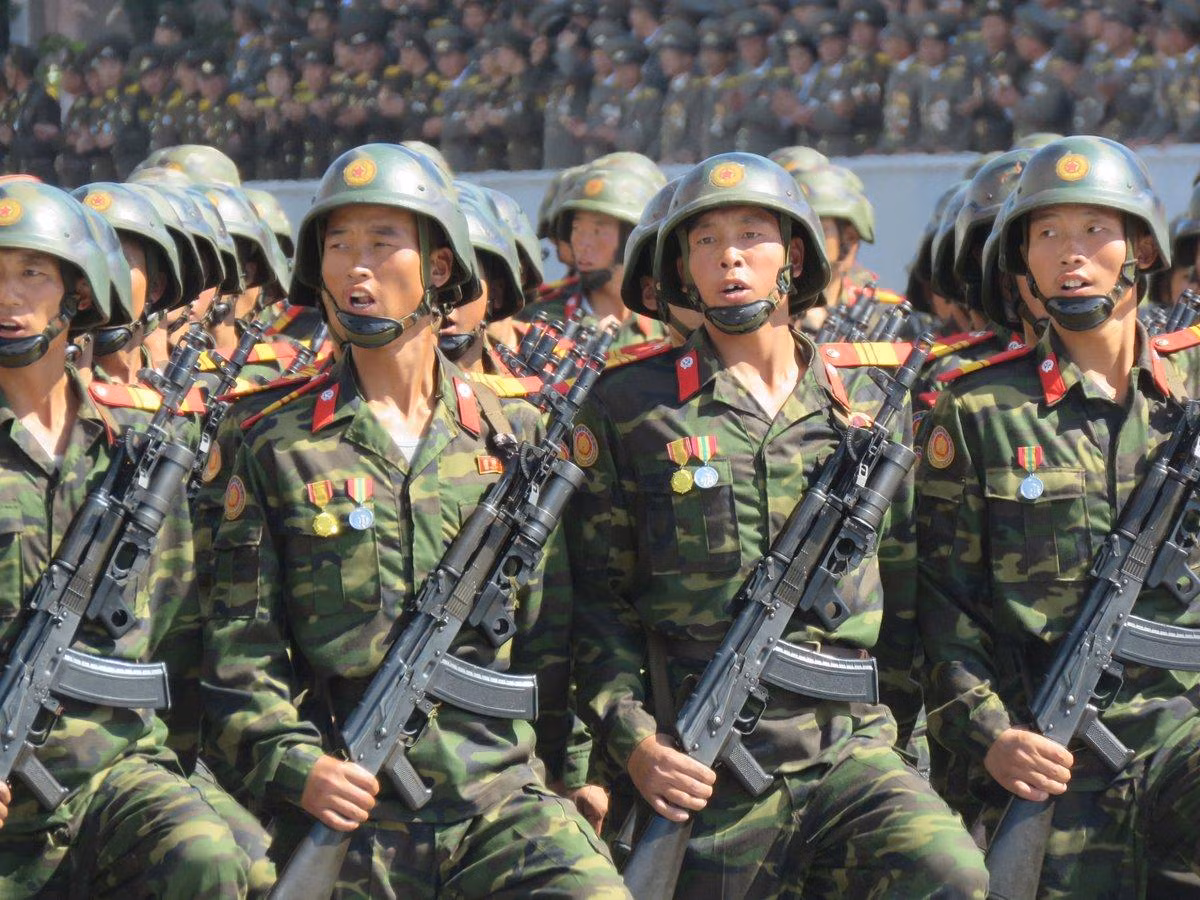 Qua thời gian dài sử dụng, Triều Tiên cũng đã có những nâng cấp nhất dịnh cho khẩu Type-88 như việc thay thế các chi tiết gỗ như tay cầm, báng súng, ốp lót tay bằng chi tiết làm bằng vật liệu tổng hợp, có độ bền cao hơn và giảm đáng kể trọng lượng súng. Ảnh: Khối chiến sĩ Triều Tiên với súng Type-88 gắn súng phóng lựu kẹp nòng.