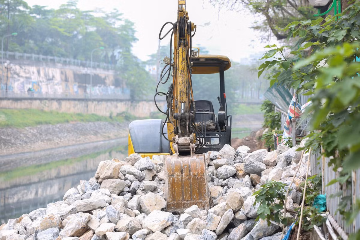 Máy xúc được huy động để ép cọc chống sạt lở, sau đó nhà thầu sẽ tiếp tục chôn ống thu gom nước thải và thi công trải bê tông, làm hố ga. 