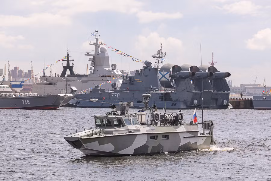 Tàu tuần tra cao tốc Project 03160 Raptor đang chạy về địa điểm neo đậu để trưng bay. Bên cạnh tàu tuần tra còn có nhiều chiến hạm khác, bao gồm cả loại tàu đổ bộ đệm khí cỡ lớn.