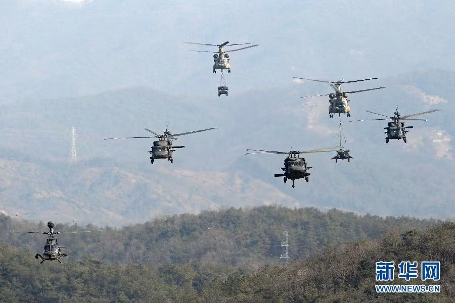 Trên trời, trực thăng vận tải CH-47 đang không vận khí tài hạng nặng với sự hộ tống của trực thăng UH-60 Black Hawk, trực thăng trinh sát OH-58D.