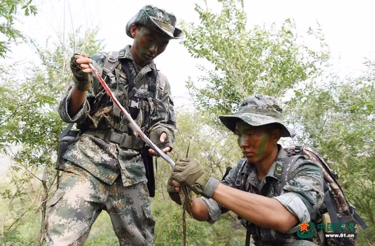 Các binh sĩ Trung Quốc phải tự mình vượt qua được các bài huấn luyện sinh tồn bắt buộc . Trong ảnh là hai binh sĩ Trung Quốc đang lột da một con rắn mà họ tìm được.