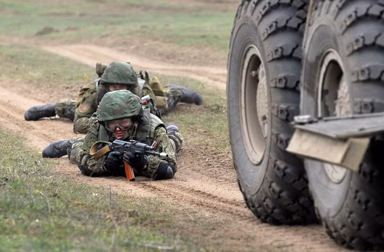 Trong ảnh là một binh sĩ Nga nấp sau lưng một chiếc xe bọc thép chở quân BTR-82AM trong đợt diễn tập vào hôm 19/3.